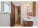 Bathroom view with wooden vanity, mirrored medicine cabinet, a doorway and window at 8731 W 89Th Pl, Broomfield, CO 80021