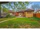 Spacious backyard featuring a lush lawn, pergola-covered patio, greenhouse, and charming brick house at 1312 Ash St, Denver, CO 80220