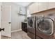 Well-lit laundry room featuring modern appliances, built-in cabinets, and laminate floors at 4077 Forever Cir, Castle Rock, CO 80109