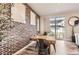 Dining area with rustic wood table and chairs, brick accent wall, and sliding door at 2932 Low Meadow Blvd, Castle Rock, CO 80109