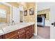 Bathroom featuring double sinks, wood cabinets, and a view into an adjacent room at 14310 Inca St, Westminster, CO 80023