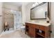 Bathroom with a shower, wood vanity, large mirror, and neutral tile at 14310 Inca St, Westminster, CO 80023