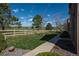 Lovely backyard with a sidewalk next to a golf field, divided by a fence with grass and trees, under a sunny blue sky at 8775 W Berry Ave # 101, Littleton, CO 80123