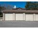 Three one car garages with white doors that correspond to a building's apartments with a paved parking lot in front at 8775 W Berry Ave # 101, Littleton, CO 80123