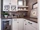 Elegant bar area features a wine refrigerator, custom cabinetry, floating shelves, and modern finishes at 6521 Barnstead Dr, Castle Pines, CO 80108