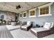 Relaxing covered patio with stone fireplace, lounge chairs, and decorative string lights at 6521 Barnstead Dr, Castle Pines, CO 80108