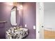 Stylish powder room featuring a marble sink, unique mirror, and purple accent wall at 265 S Monroe St, Denver, CO 80209