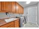 Functional laundry room with wood cabinets, a utility sink, and modern washer and dryer units at 10233 Greatwood Ct, Highlands Ranch, CO 80126
