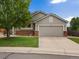 Charming single-Gathering home features a two-car garage, brick accents, a lush lawn, and mature trees at 386 Monte Vista St, Brighton, CO 80601