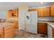Open kitchen with tile floors, wooden cabinets, updated refrigerator, and adjacent breakfast bar countertop at 386 Monte Vista St, Brighton, CO 80601