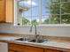 Close-up of a stainless steel kitchen sink with a large window overlooking the exterior greenery at 386 Monte Vista St, Brighton, CO 80601