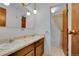 Well-lit bathroom with dual sinks, wood cabinets, and a separate toilet and shower area at 8204 S Cody St, Littleton, CO 80128