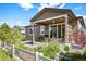 Charming home exterior with a covered patio, lush landscaping, and a white picket fence at 18067 E Anthem Dr, Parker, CO 80134