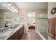 Bright bathroom showcasing a double vanity, granite countertop, and seamless glass shower with view into the main bedroom at 18067 E Anthem Dr, Parker, CO 80134