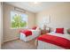 Bright bedroom featuring twin beds with red accents, a nightstand, and a large window at 18067 E Anthem Dr, Parker, CO 80134