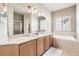 Bright bathroom featuring double sinks with a granite countertop, large mirror, and a separate tub at 16534 E Fire Fly Ave, Parker, CO 80134