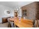 Dining room with a brick wall, a modern chandelier, and a large wood table with seating for eight at 9142 Warriors Mark Dr, Franktown, CO 80116