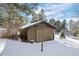 Wooden shed nestled in a snow-covered landscape, surrounded by mature trees at 9142 Warriors Mark Dr, Franktown, CO 80116