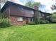 Spacious backyard featuring lush green grass, trees, and a brick and wood exterior at 12075 W 18Th Dr, Lakewood, CO 80215
