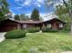 Charming single-story home with brick and wood exterior, lush green lawn, and mature trees at 12075 W 18Th Dr, Lakewood, CO 80215