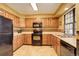 Galley kitchen with wood cabinets, black appliances, and tile floor at 4618 S Newton St, Denver, CO 80236