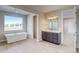 Bright bathroom featuring a soaking tub, vanity with dark cabinets, and tile floors at 8596 Hotchkiss St, Littleton, CO 80125