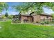 Well-manicured backyard with lush lawn, mature trees, and a covered patio at 5185 W Fair Pl, Littleton, CO 80123