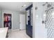 Bathroom featuring blue vanity with drawers, tiled shower, and closet with custom shelving at 5185 W Fair Pl, Littleton, CO 80123