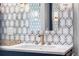 Close up of bathroom vanity with geometric backsplash, gold faucets, and white countertop at 5185 W Fair Pl, Littleton, CO 80123