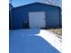View of the detached one-car garage with white door and blue siding at 313 W 3Rd Ave, Byers, CO 80103