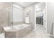 Bathroom featuring a soaking tub, a walk-in shower, and an adjacent custom walk-in closet at 18922 W 84Th Ave, Arvada, CO 80007