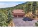 Stunning aerial view of a house with a three car garage surrounded by lush greenery and a driveway at 7790 S Homesteader Dr, Morrison, CO 80465