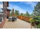 Outdoor deck with dining area overlooking lush landscape, with mature trees and blooming flowers at 7790 S Homesteader Dr, Morrison, CO 80465