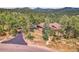 Rustic-style home nestled in a lush forest setting with a winding driveway and mountain views at 7790 S Homesteader Dr, Morrison, CO 80465