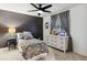 Bright bedroom with a grey accent wall, ceiling fan, window with patterned curtains, and white dresser at 10546 Sundial Rim Rd, Highlands Ranch, CO 80126