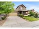 View of a home with a covered porch, large driveway, well-kept landscaping, and tan exterior at 10546 Sundial Rim Rd, Highlands Ranch, CO 80126