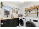 Functional laundry room with modern washer/dryer, cabinets, wood countertop and floating shelves at 10546 Sundial Rim Rd, Highlands Ranch, CO 80126