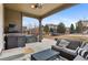 Covered patio with wicker furniture, tv, stone surround, and hot tub overlooking the spacious backyard at 10546 Sundial Rim Rd, Highlands Ranch, CO 80126