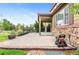 Inviting patio area features a stone facade, ceiling fan, manicured lawn, mature greenery, and sprinkler system at 10546 Sundial Rim Rd, Highlands Ranch, CO 80126