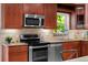 Modern kitchen with stainless steel appliances, wood cabinets, and a large window for natural light at 6402 Iris Ct, Arvada, CO 80004