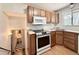 Efficient kitchen features stainless steel appliances, wooden cabinetry, and stairs leading to a lower level with a bathroom at 7195 E Louisiana Ave, Denver, CO 80224