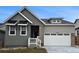 Charming home featuring a two-car garage, stone accents, gray siding, and stylish black window awnings at 17146 W 92Nd Loop, Arvada, CO 80007
