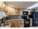 Kitchen with wood cabinets, black appliances, and tile flooring at 1869 S Union Blvd, Lakewood, CO 80228