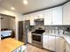 Updated kitchen with white cabinets, stainless steel appliances, and adjacent bedroom at 2285 S Knox Ct, Denver, CO 80219