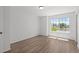 Sunlit bedroom with wood-look flooring and a large window overlooking the green outdoors at 19817 E 47Th Pl, Denver, CO 80249