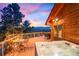 Outdoor deck with a hot tub, dining area, and scenic sunset views provides an ideal setting for relaxation and entertainment at 394 S Ponderosa Way, Evergreen, CO 80439