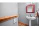 Stylish powder room features a pedestal sink, framed mirror, and hardwood floors, ideal for guests at 394 S Ponderosa Way, Evergreen, CO 80439