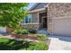 Inviting entrance with stone details, green lawn and garden bed, showcasing the home's curb appeal at 13986 Lexington Dr, Parker, CO 80134