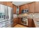 Gourmet kitchen with stainless steel appliances, stone backsplash, and rich wood cabinetry at 13986 Lexington Dr, Parker, CO 80134