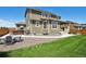 Exterior backyard view of a home with green siding, a well-kept lawn, a covered patio and a hot tub at 16188 Elizabeth St, Thornton, CO 80602